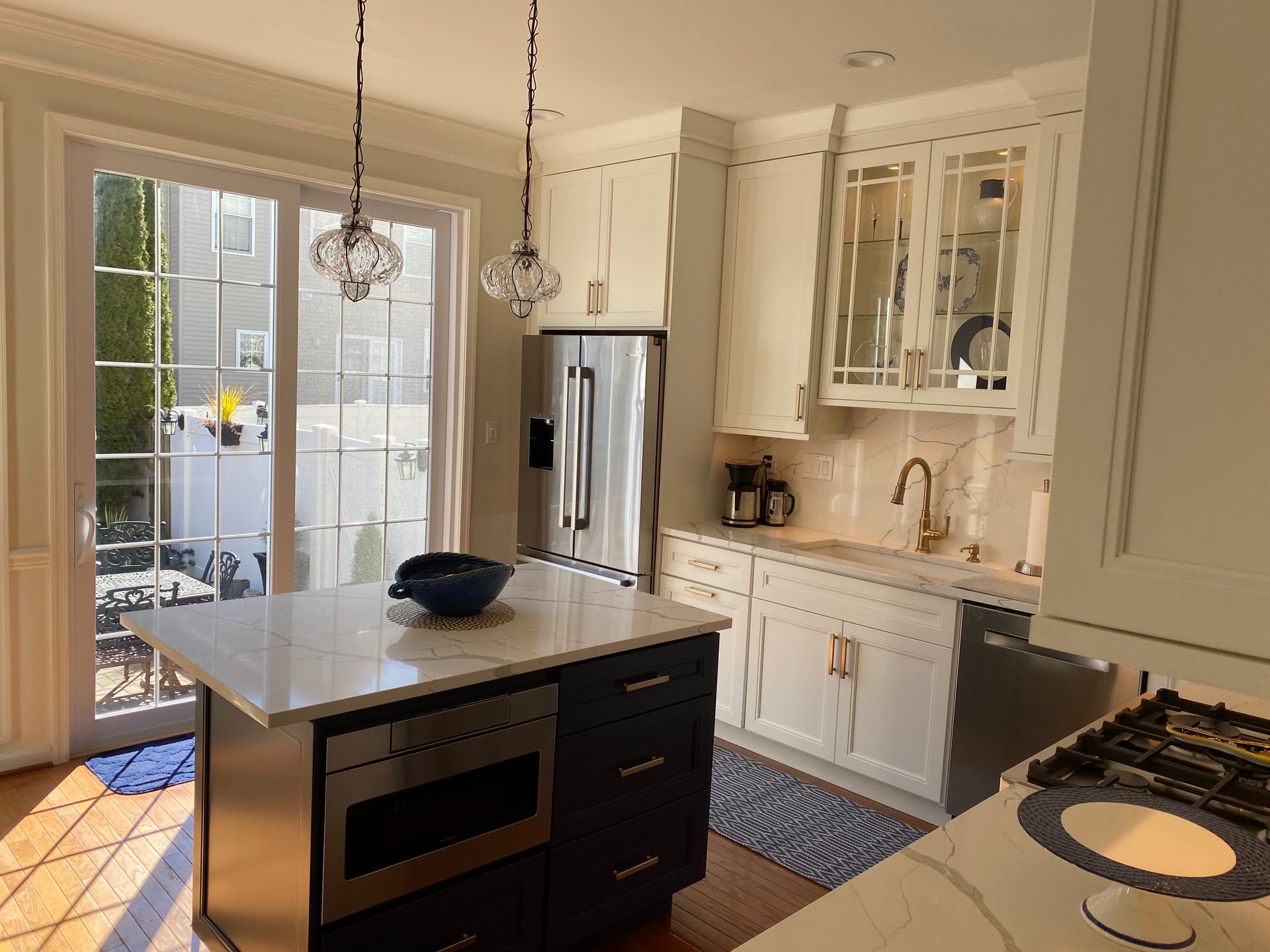 A kitchen with white cabinets , stainless steel appliances , and a large island.
