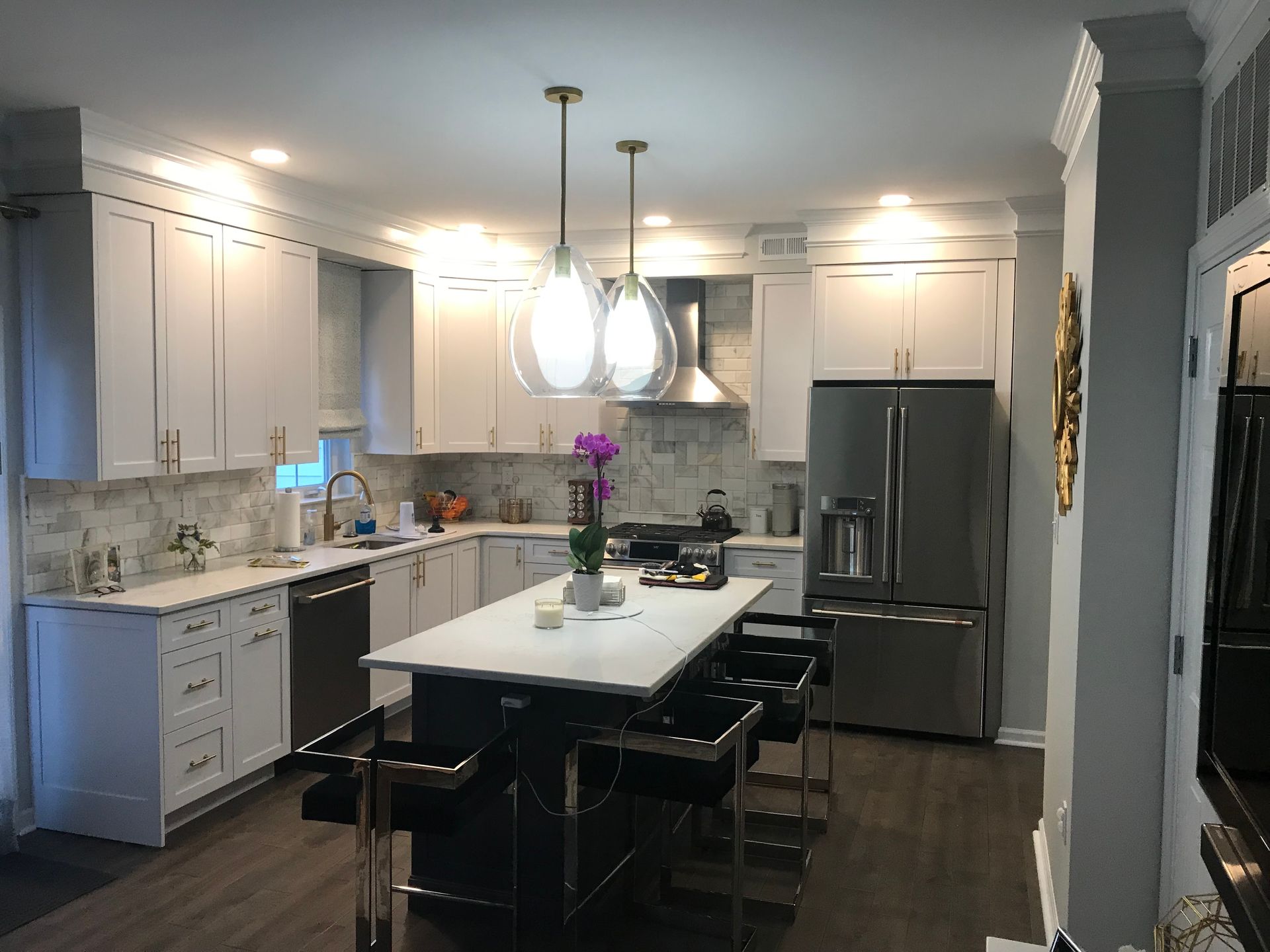 A kitchen with white cabinets , stainless steel appliances and a large island.