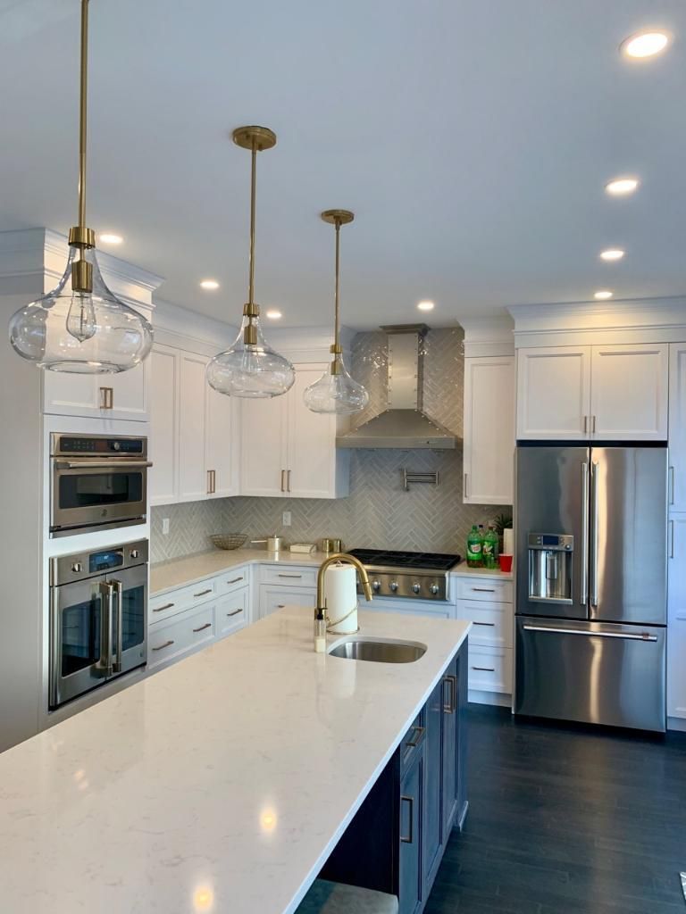 A kitchen with white cabinets , stainless steel appliances , and a large island.