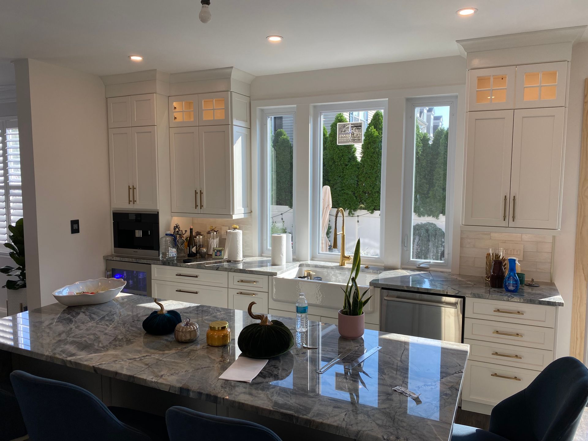 A kitchen with white cabinets , granite counter tops , stainless steel appliances and a large island.