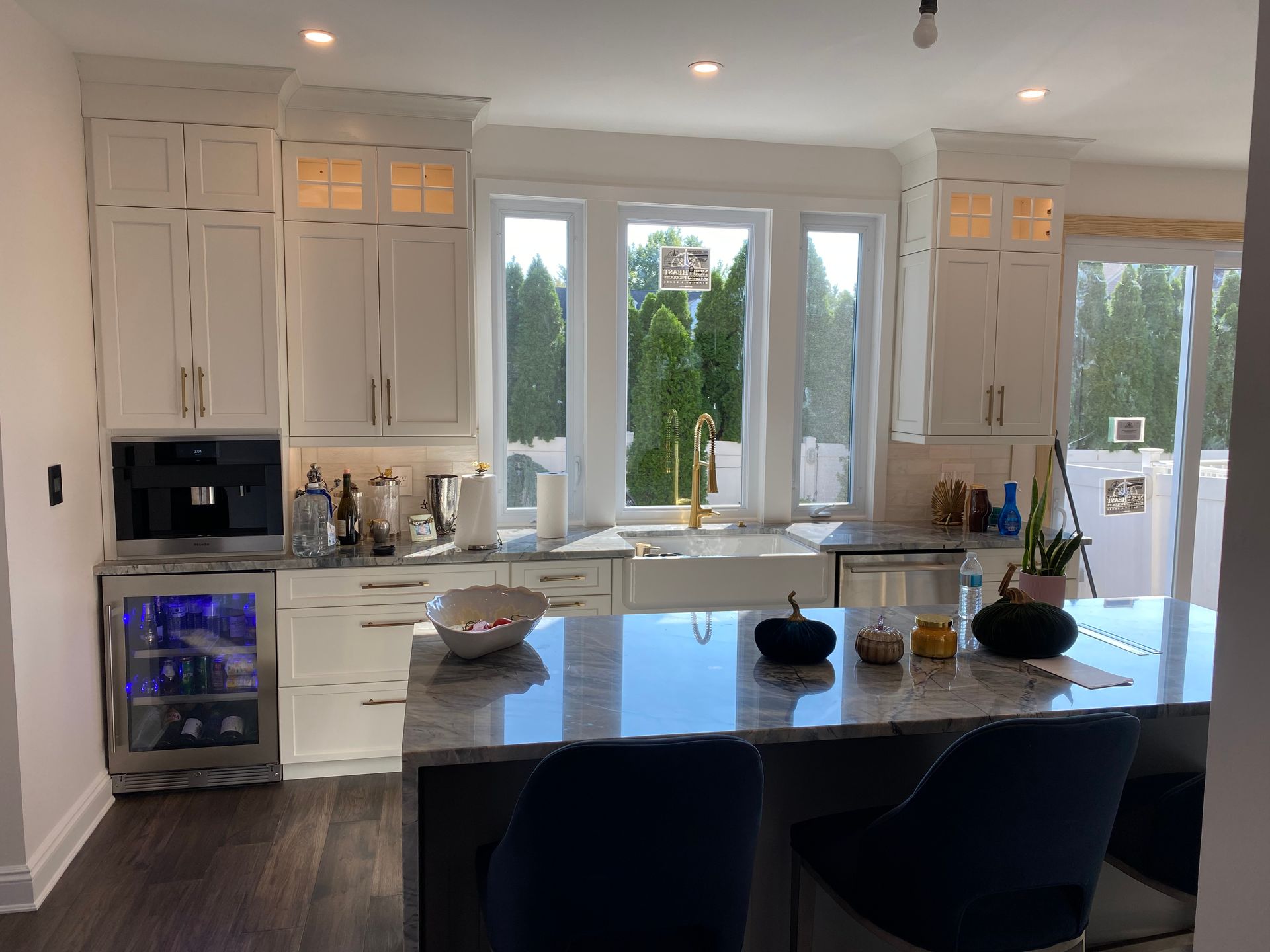 A kitchen with white cabinets , granite counter tops , a refrigerator and a sink.
