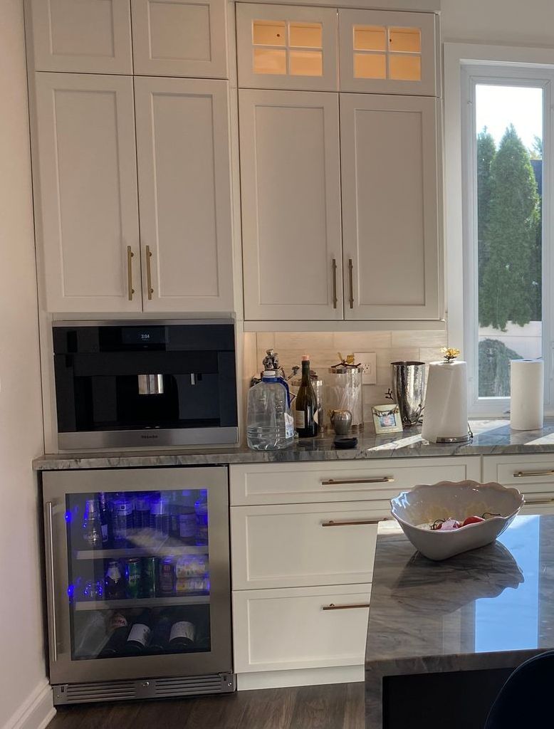 A kitchen with white cabinets , stainless steel appliances and a wine cooler.