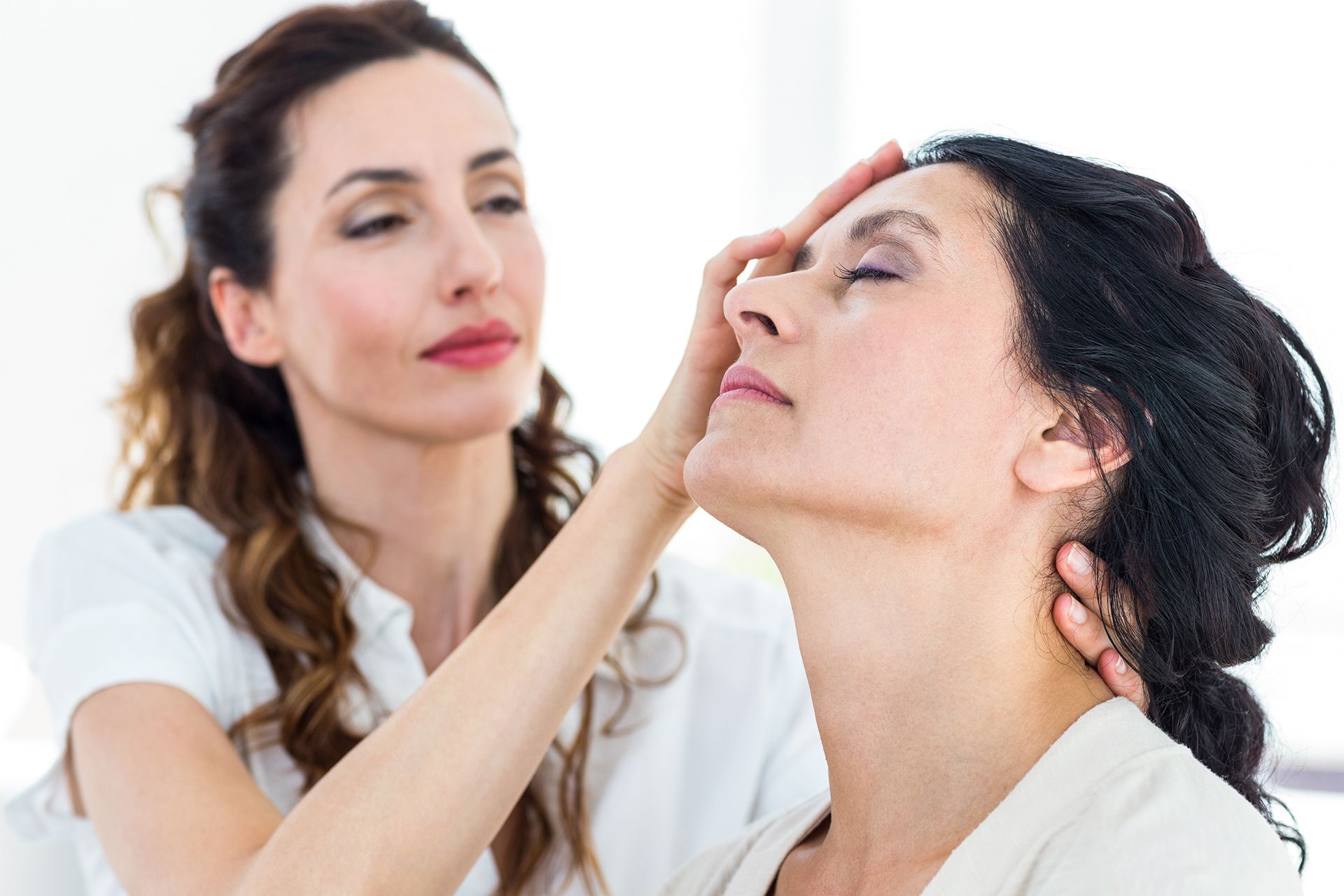 Woman receiving head and neck massage in a bright room.