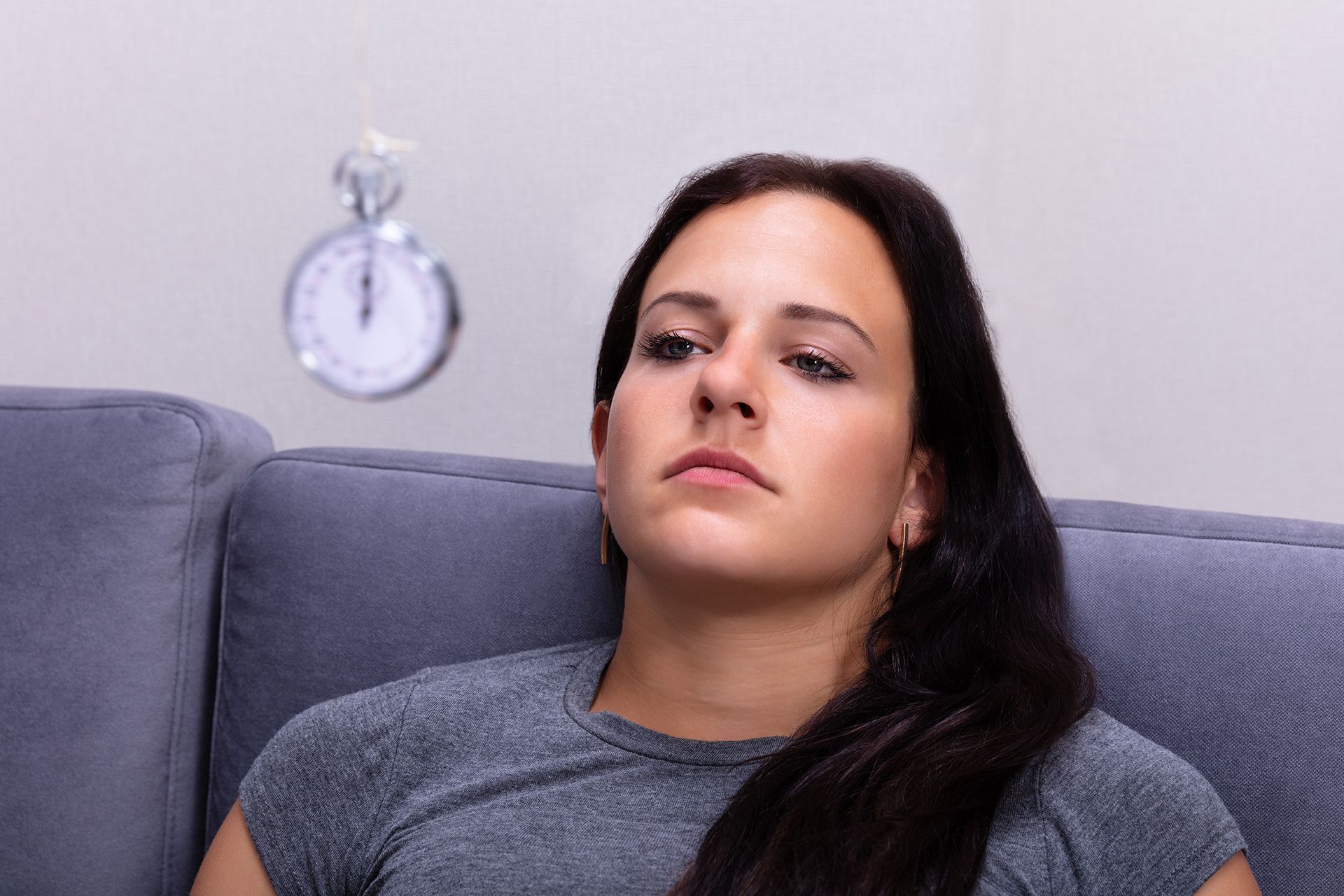 Woman on couch, eyes closed, with a floating stopwatch above.