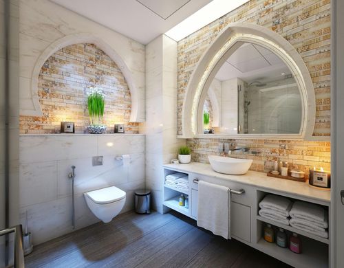 Luxurious bathroom with arched mirror and tiled walls, featuring a toilet, sink, and towels.