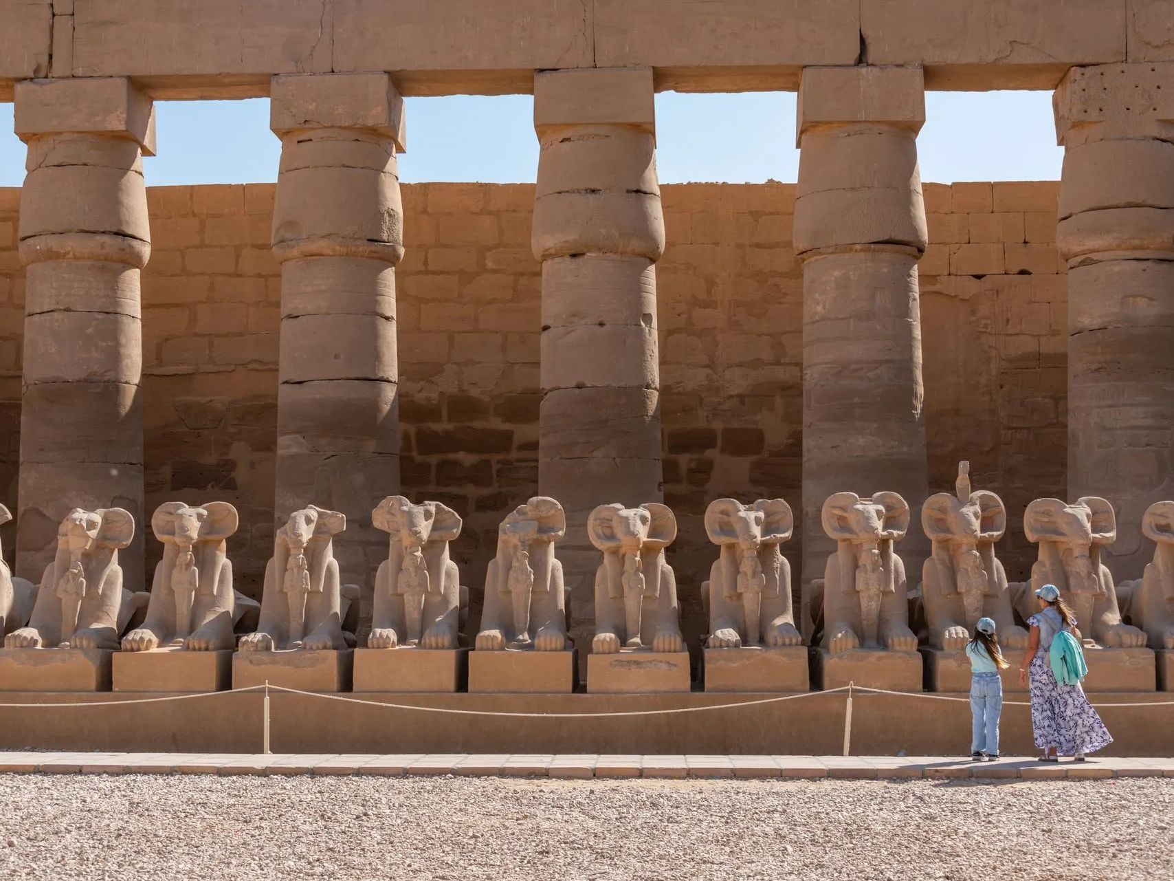 Two people are standing in front of a row of statues.