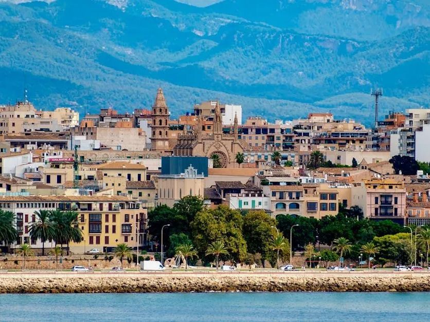 A city with mountains in the background and a body of water in the foreground