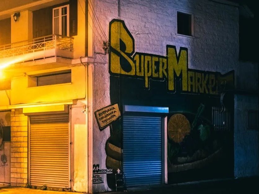 A supermarket with a yellow sign on the side of it at night.