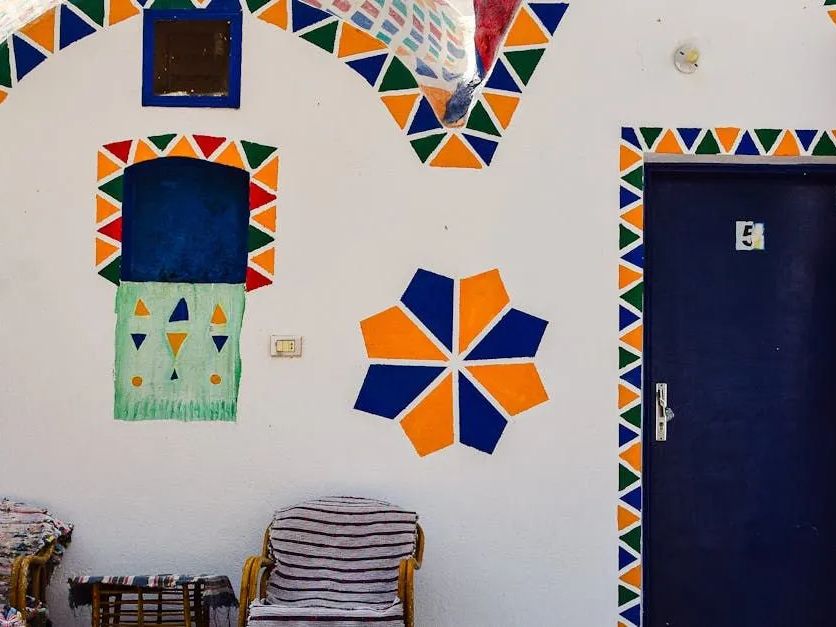 A white wall with a blue door and a chair painted on it