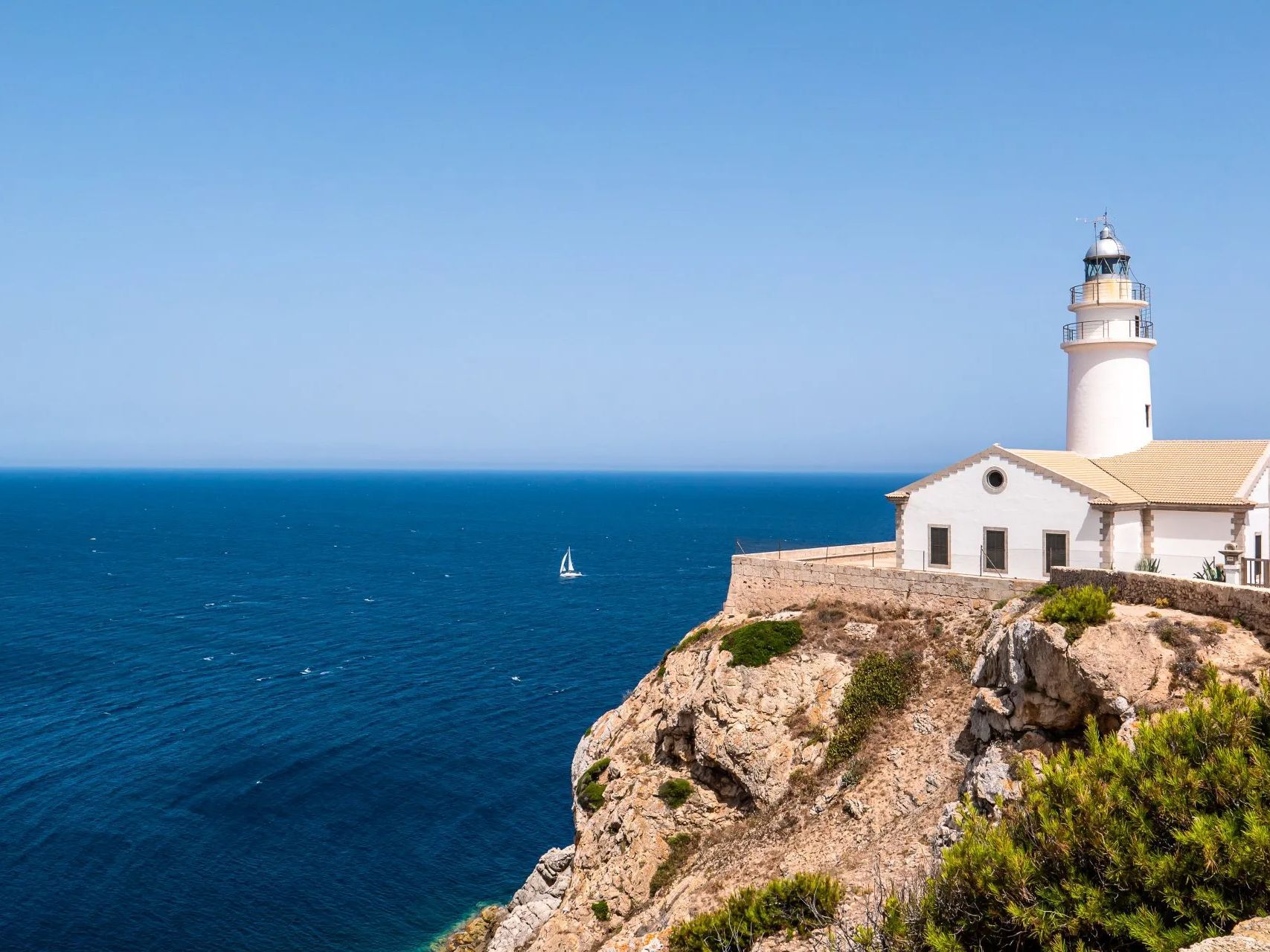 A lighthouse is sitting on top of a cliff overlooking the ocean.