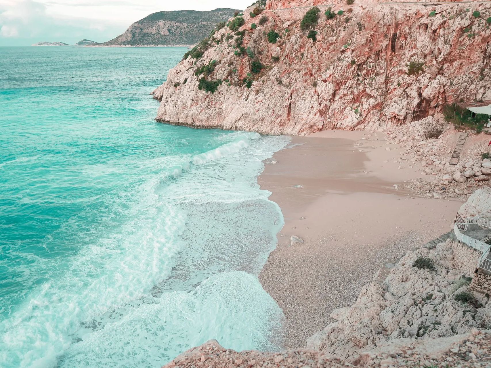 A beach surrounded by rocks and cliffs next to a body of water.