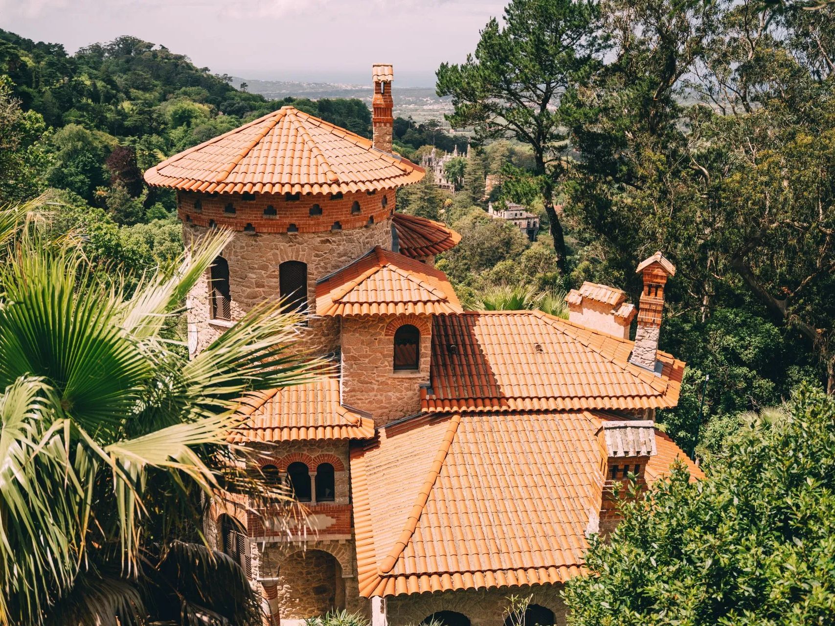 A large house with a tiled roof is surrounded by trees.