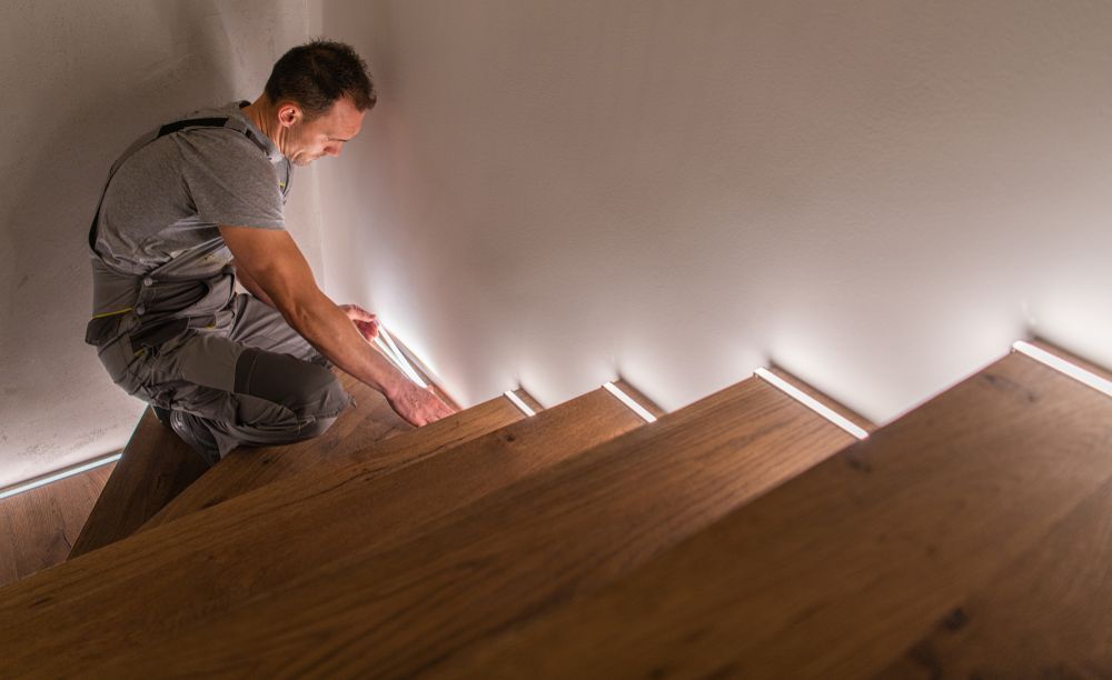 Person Installs Led Strip Lighting on Wooden Staircase — Elite Electrical Ballarat in Delacombe, VIC