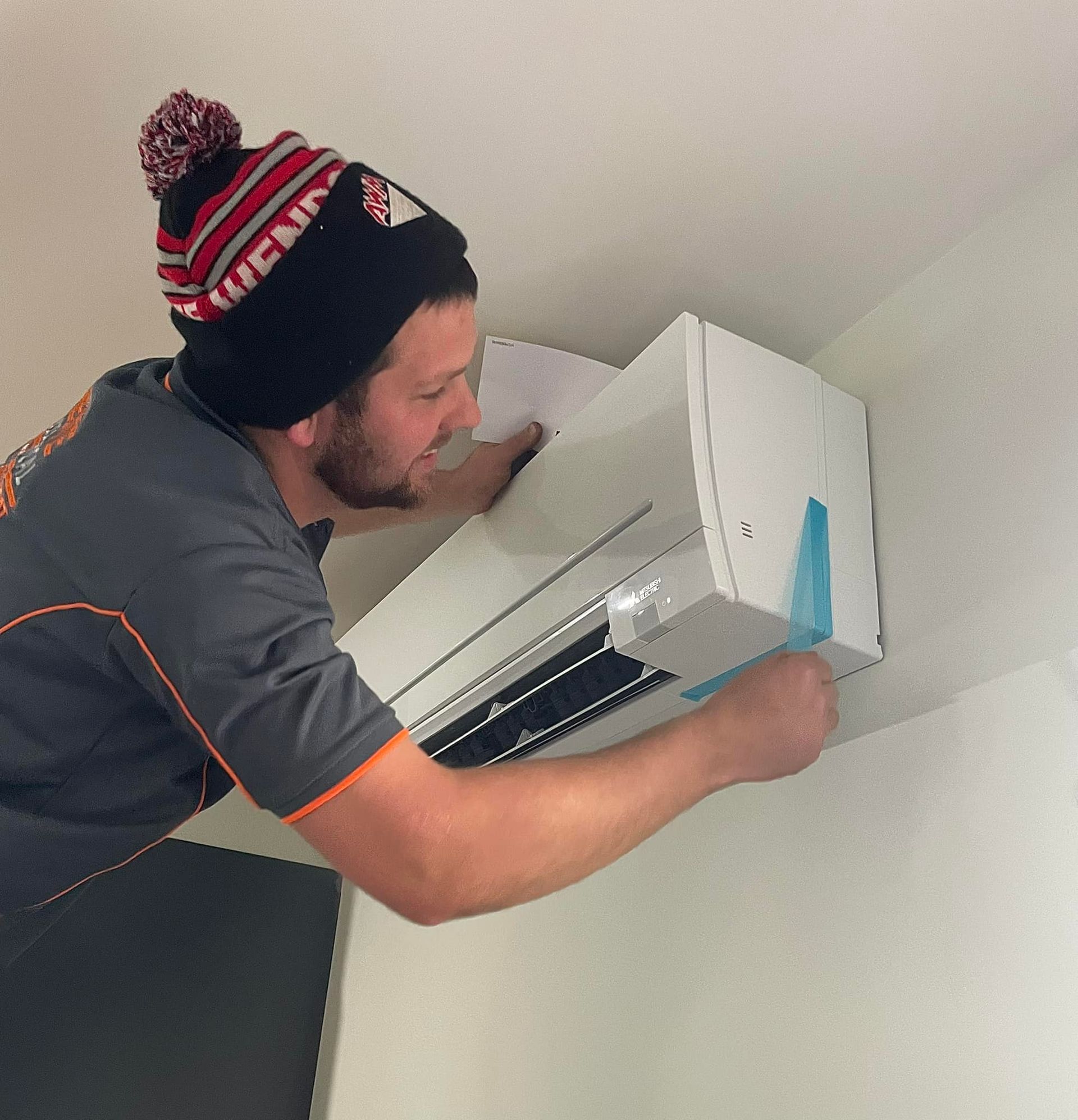 Man in a Beanie Installing an Air Conditioner — Elite Electrical Ballarat in Delacombe, VIC