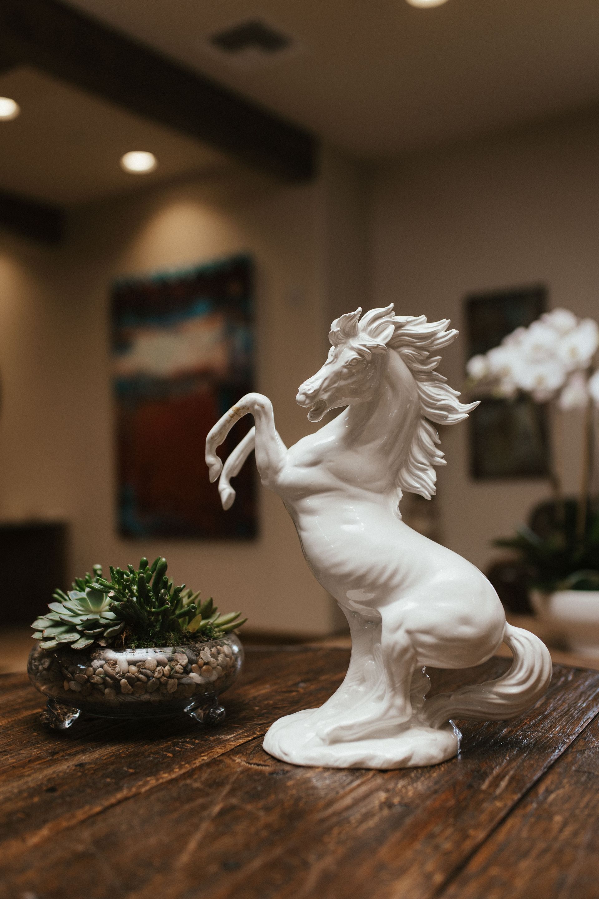 A white statue of a horse is standing on its hind legs on a wooden table.