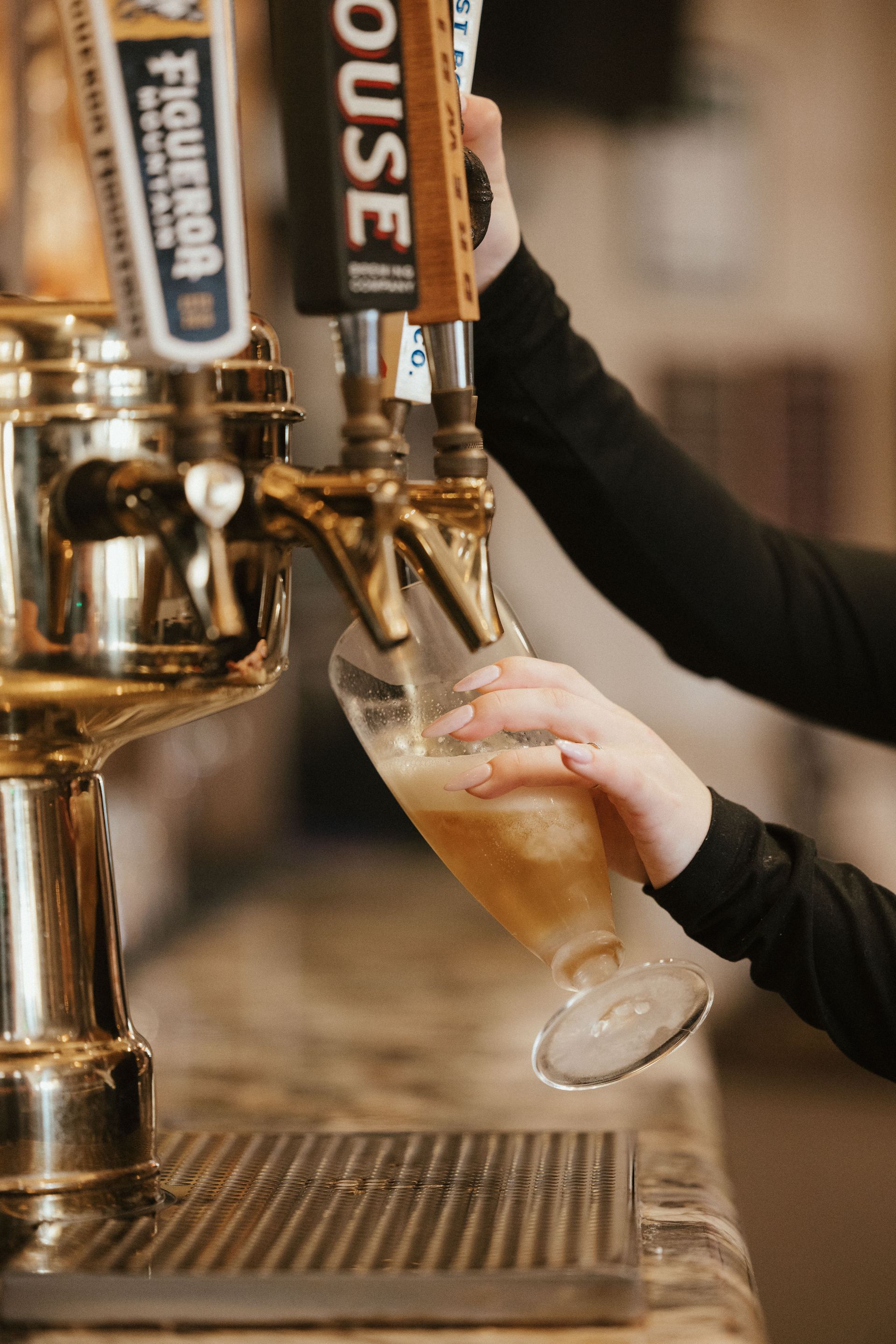 A person is pouring beer from a tap into a glass.