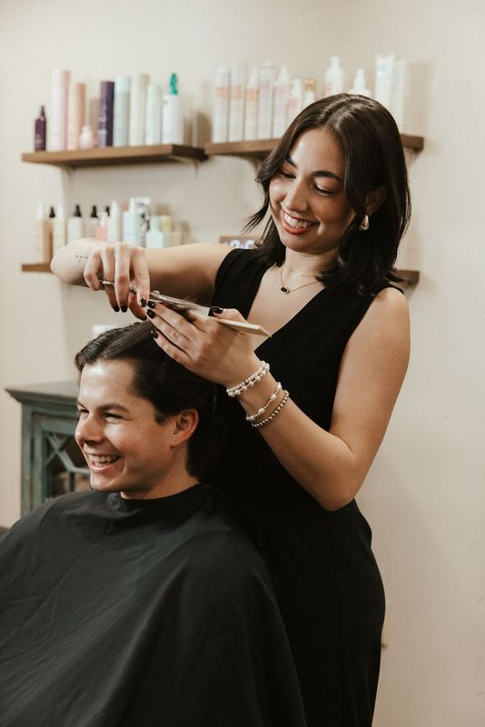 A woman is cutting a man 's hair in a salon.