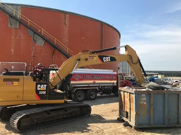 Excavator Loading a Dumpster Into a Truck — Jacksonville, FL — Paul Murray Oil Inc
