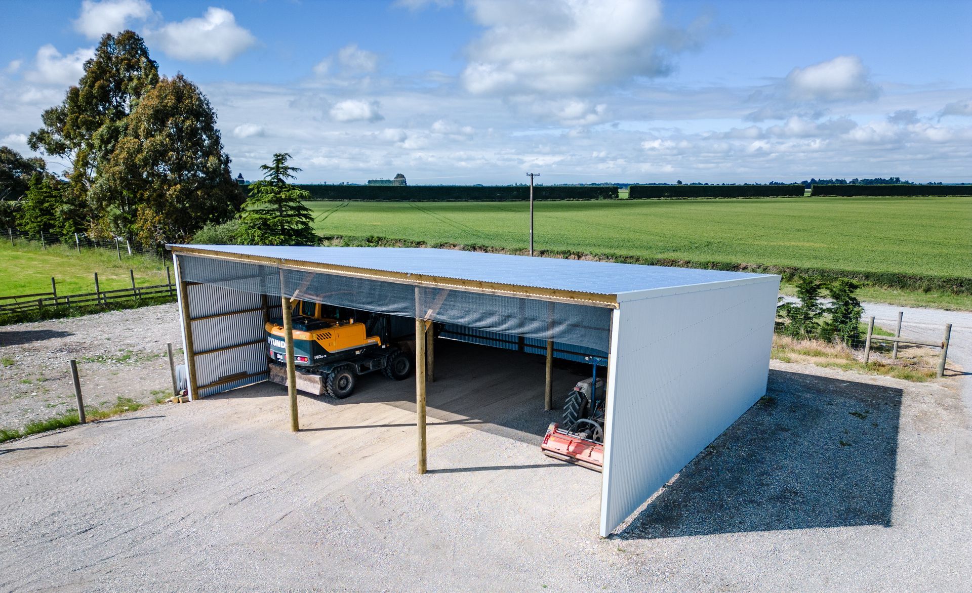A white shed with a yellow truck parked underneath it.