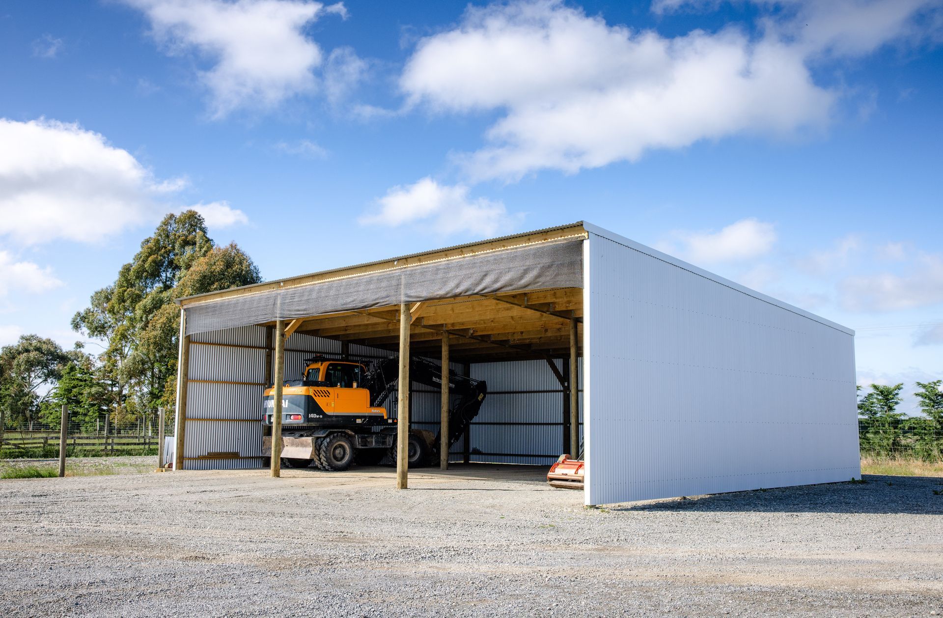 A yellow truck is parked under a white building.