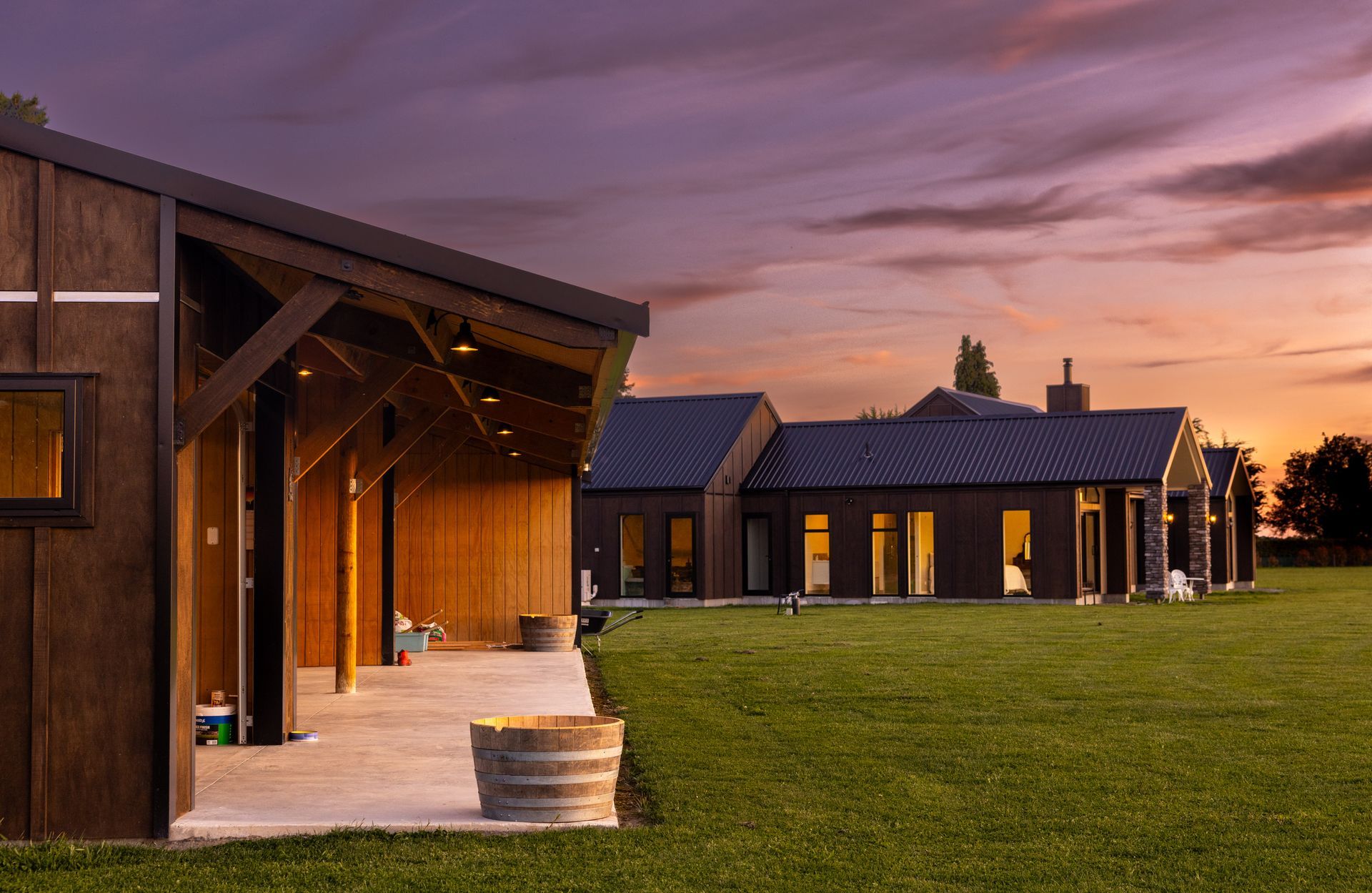 A row of houses sitting on top of a lush green field at sunset.
