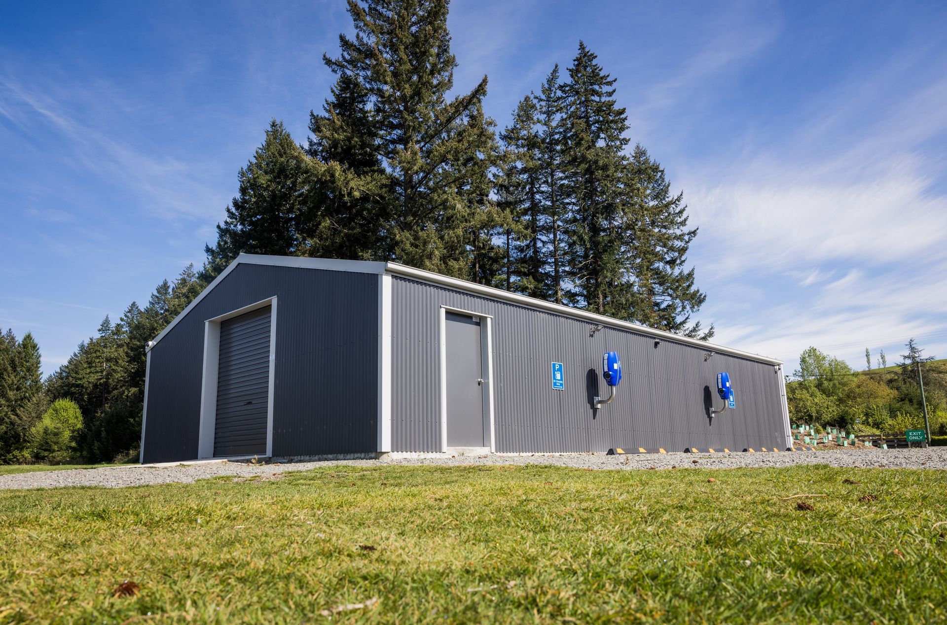 A large gray building is sitting in the middle of a grassy field.