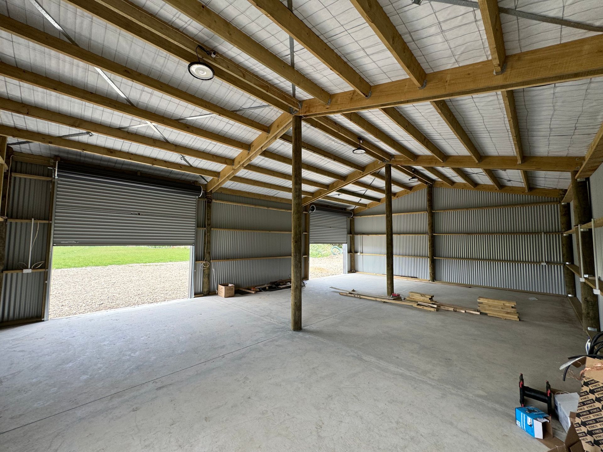 A large empty building with a concrete floor and wooden beams