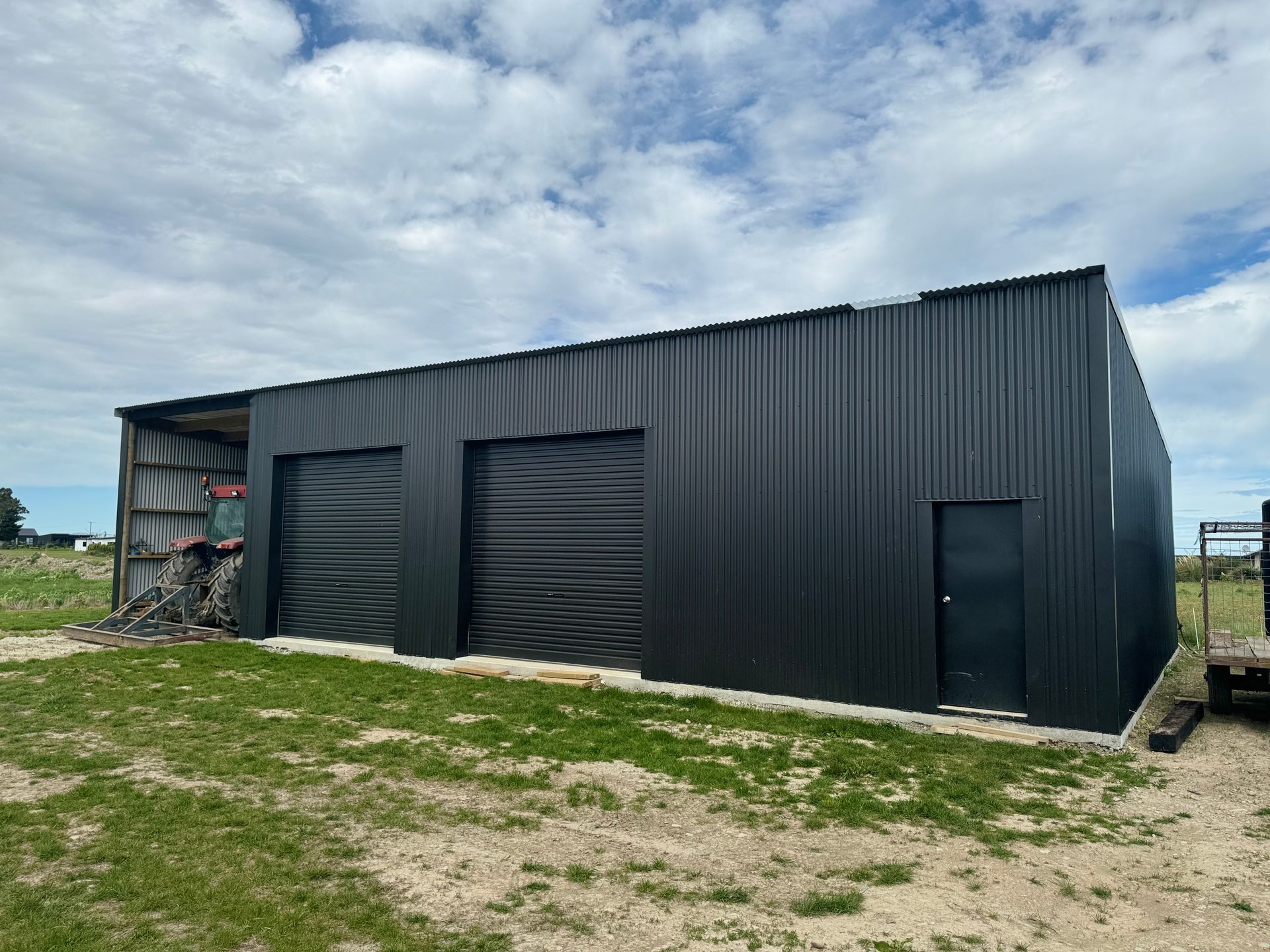 A large black building is sitting in the middle of a grassy field.