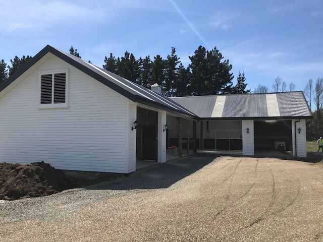 A white house with a black roof and a driveway