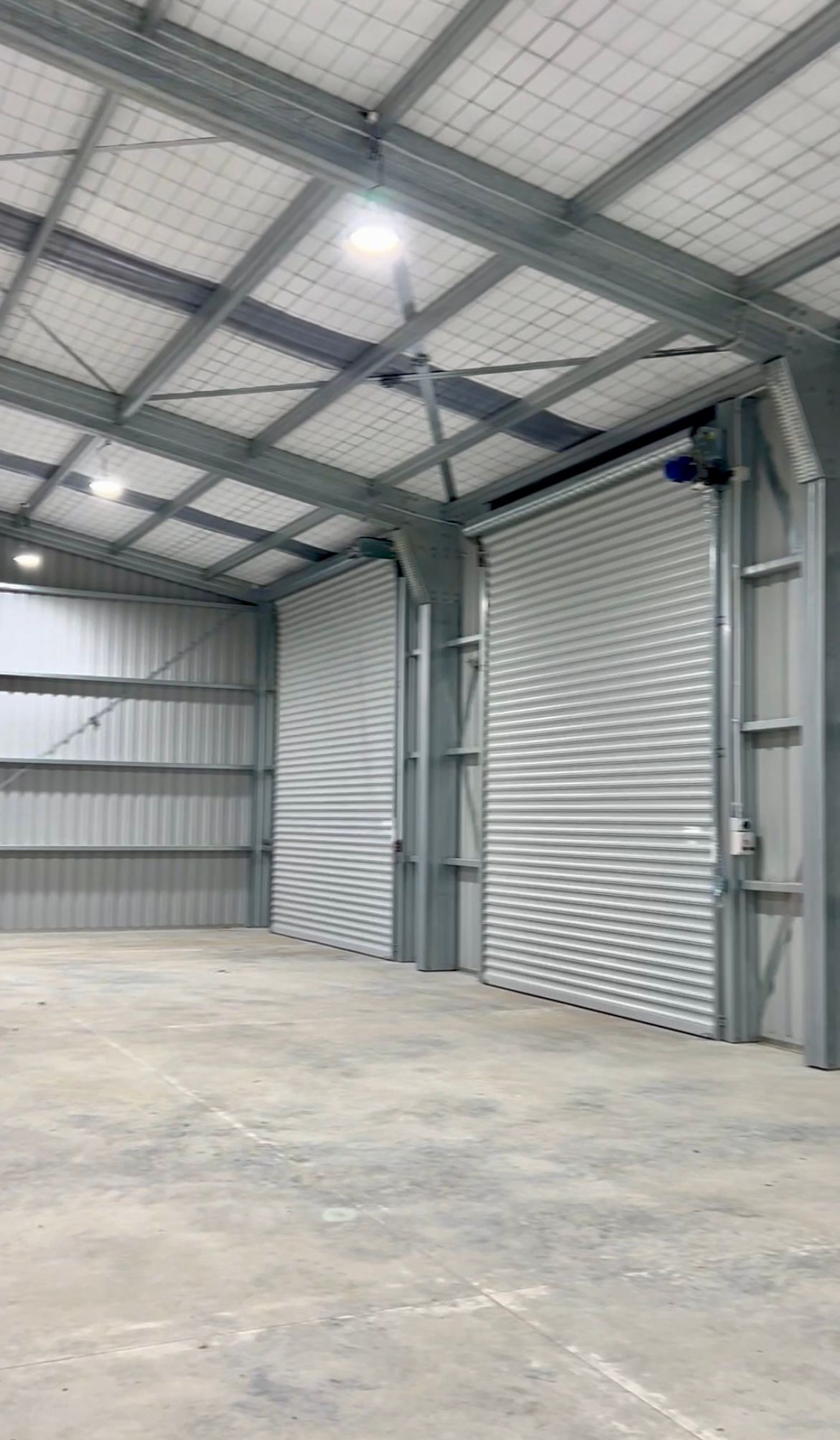 A large warehouse with a lot of doors and a concrete floor.