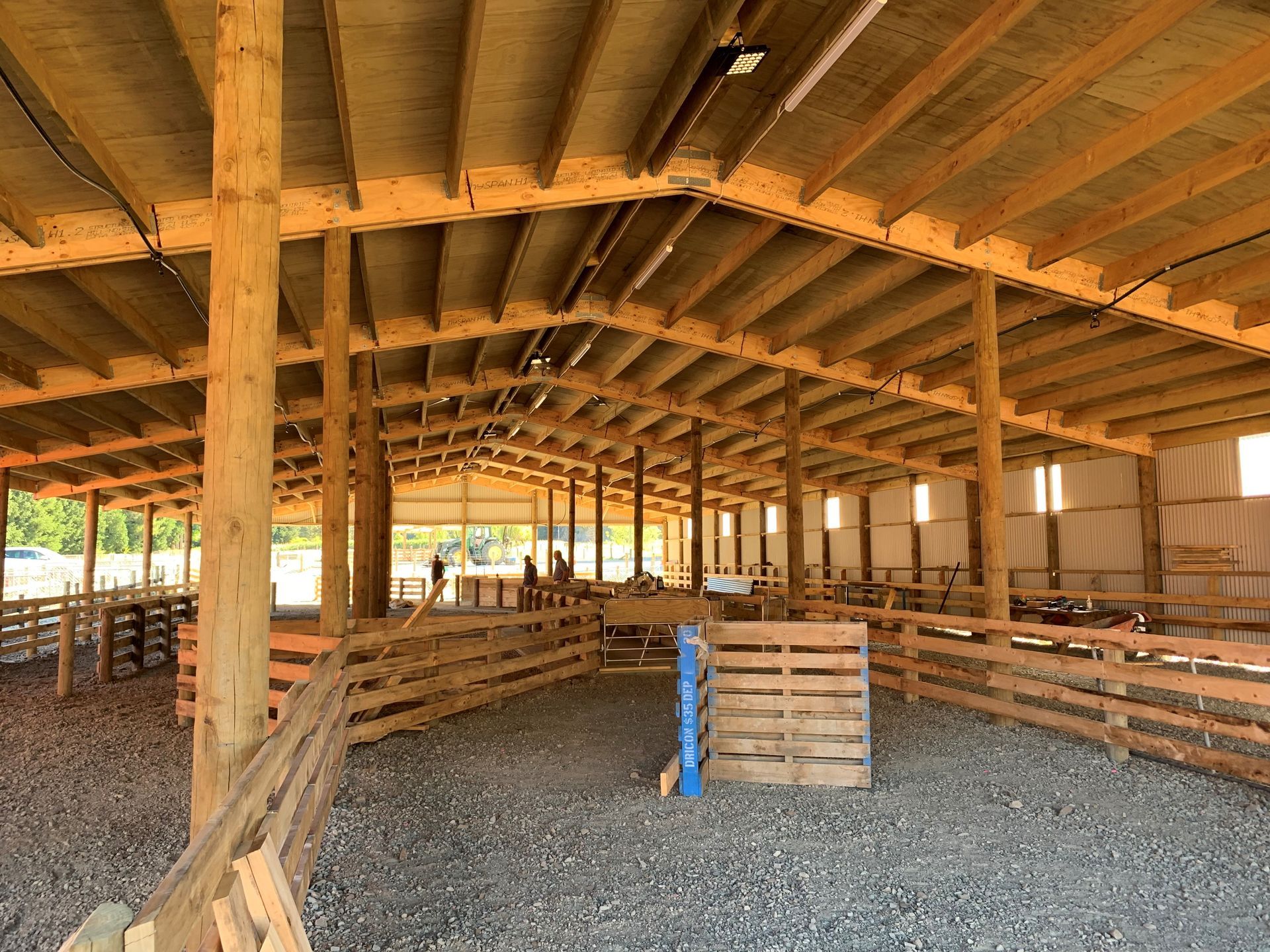 The inside of a large wooden barn with a fence around it.