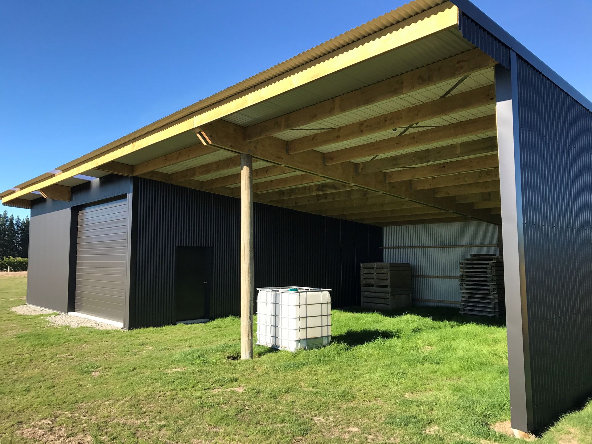 A large shed is sitting in the middle of a grassy field.