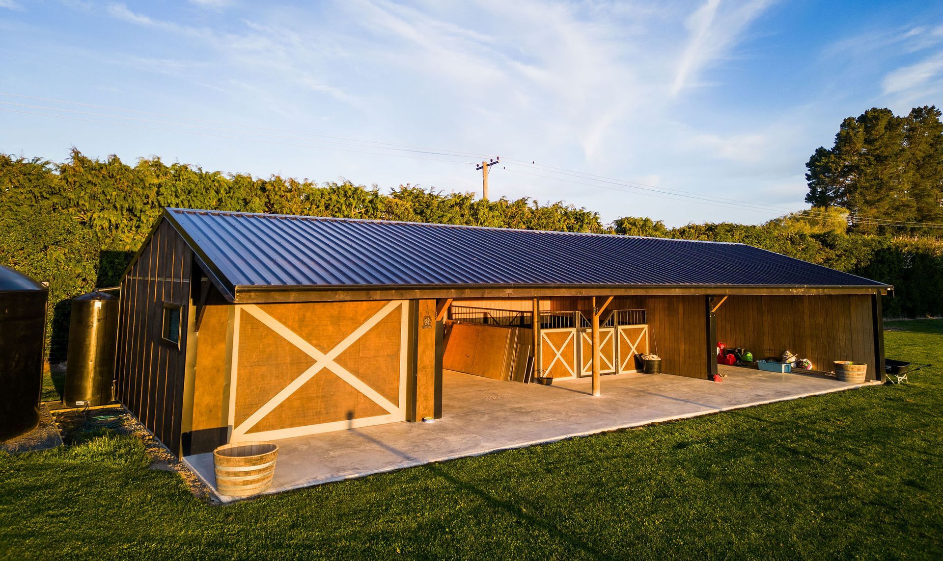 A large barn with a blue roof is sitting in the middle of a grassy field.