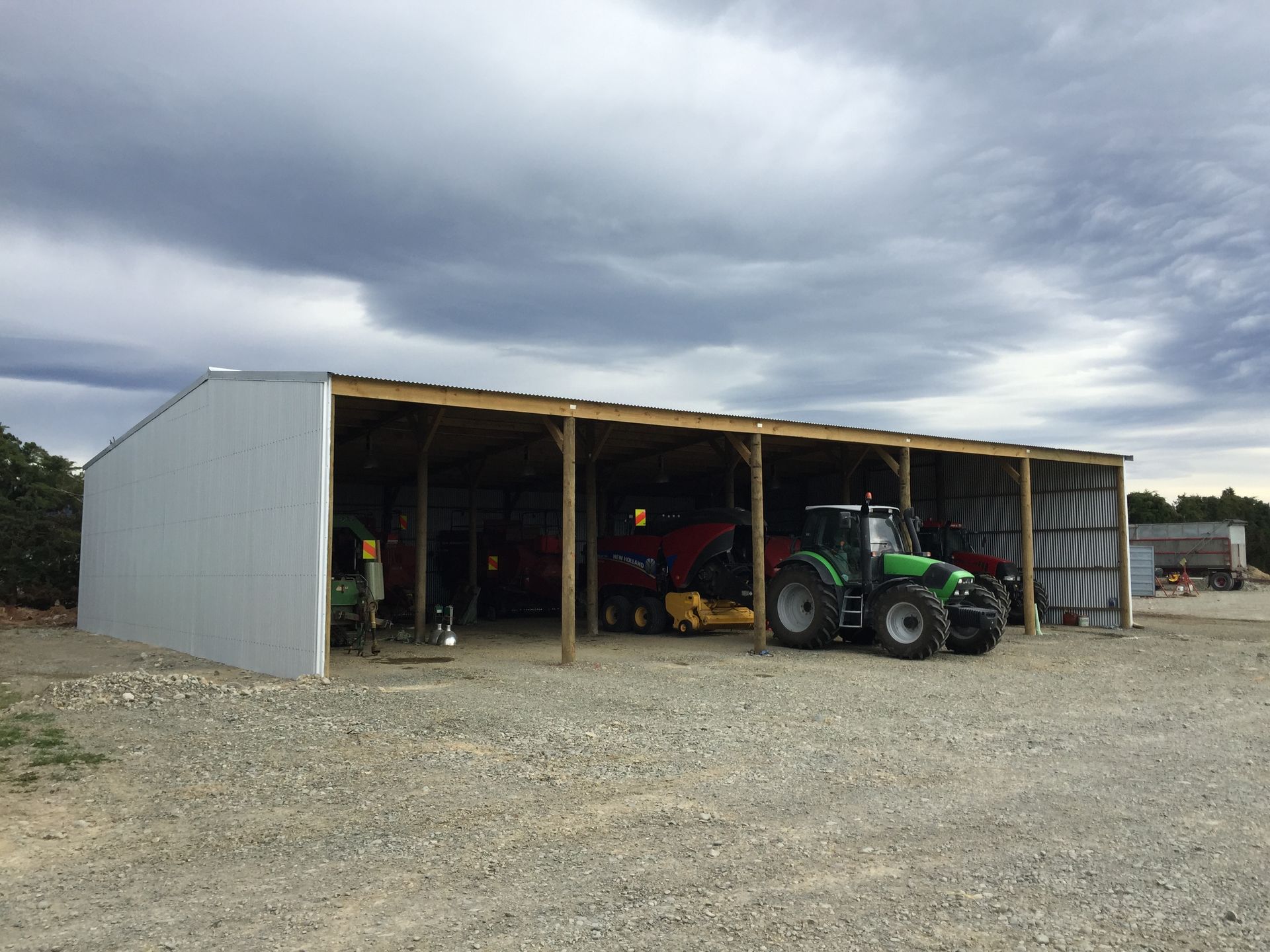 A green tractor is parked in front of a shed.