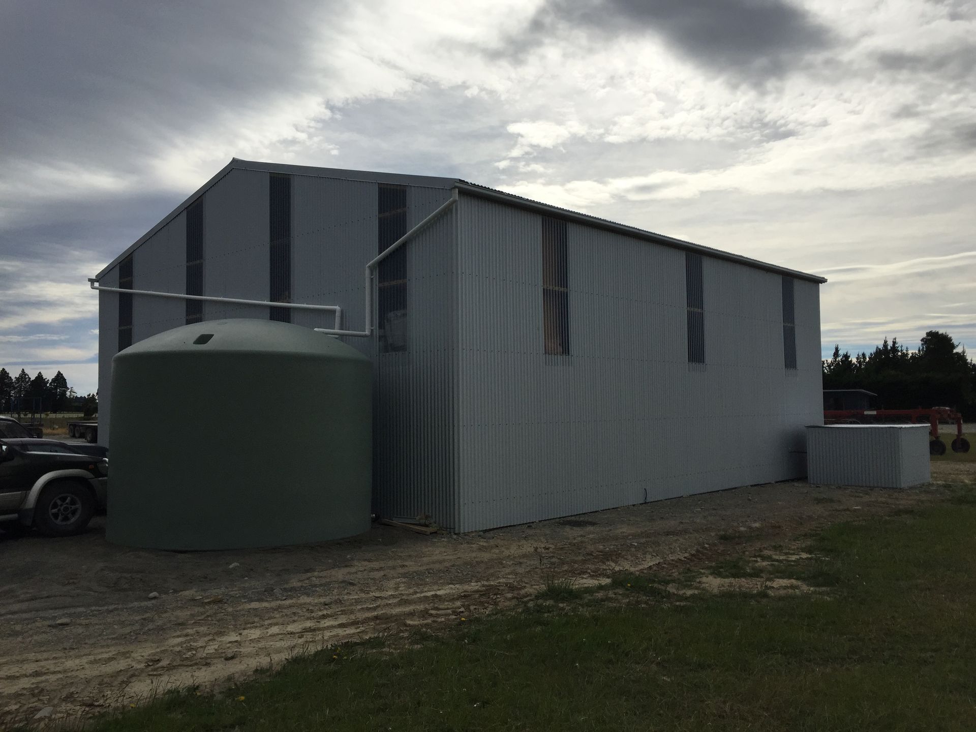 A large white building with a green water tank in front of it.