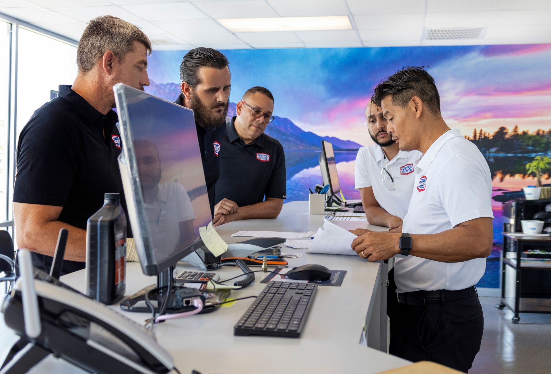 Group of AAMCO team members reviewing service orders at the AAMCO Center in Port Richey, FL.