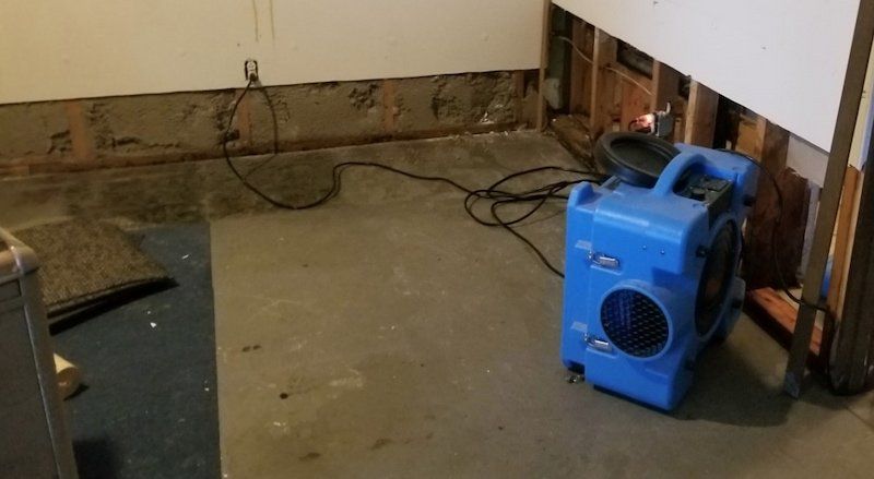 A blue fan is sitting on the floor of a room next to a wall.