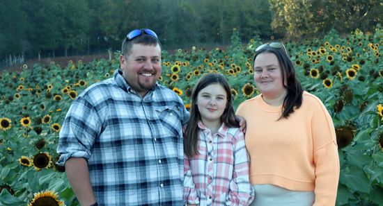 A family posing for a picture in front of a field of sunflowers