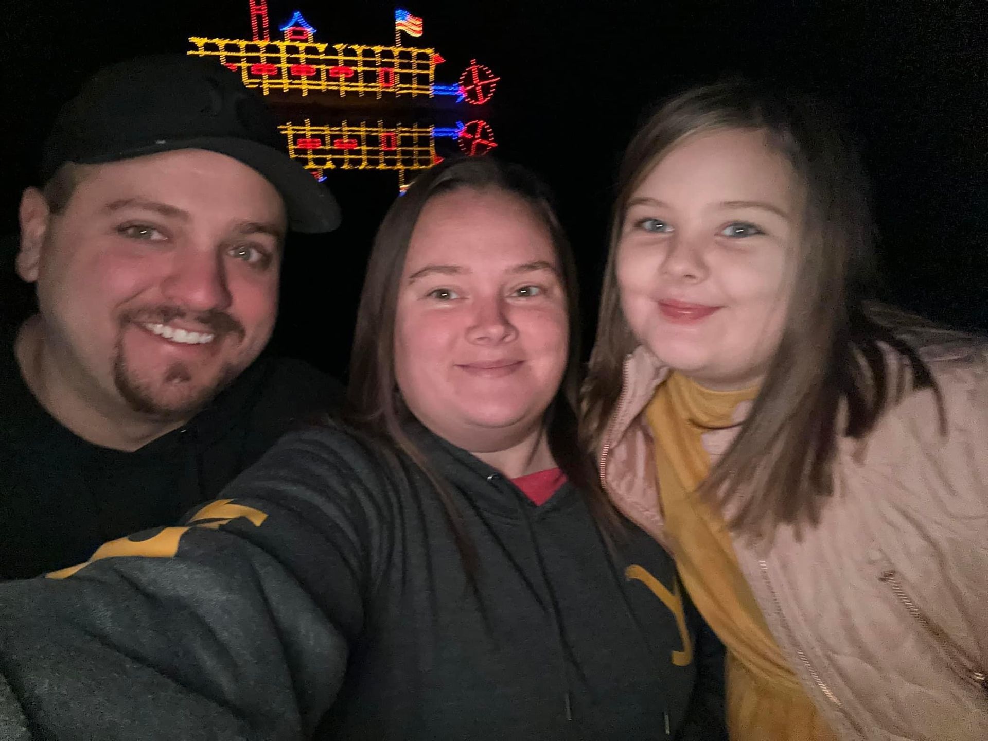 A man and two women are posing for a picture in front of a christmas tree.