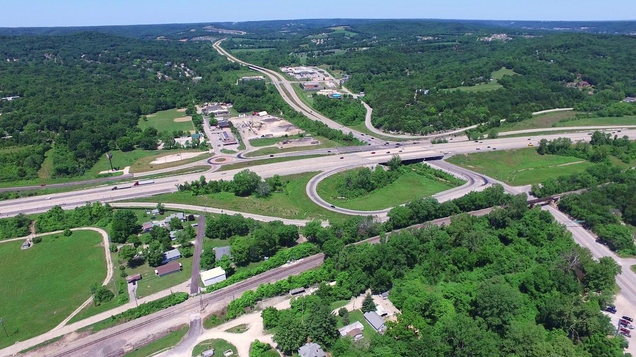An aerial view of a highway surrounded by trees and fields.