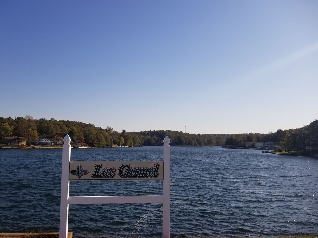 A lake with a sign in the foreground and a blue sky in the background.