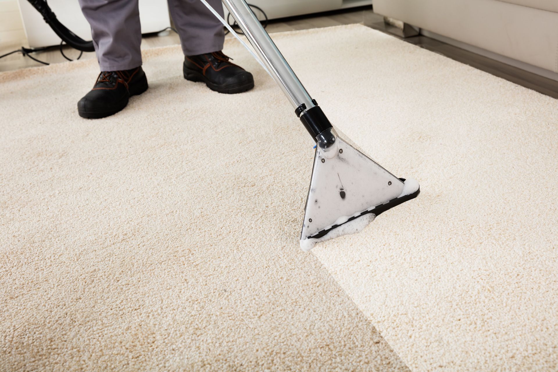 A person is cleaning a carpet with a vacuum cleaner