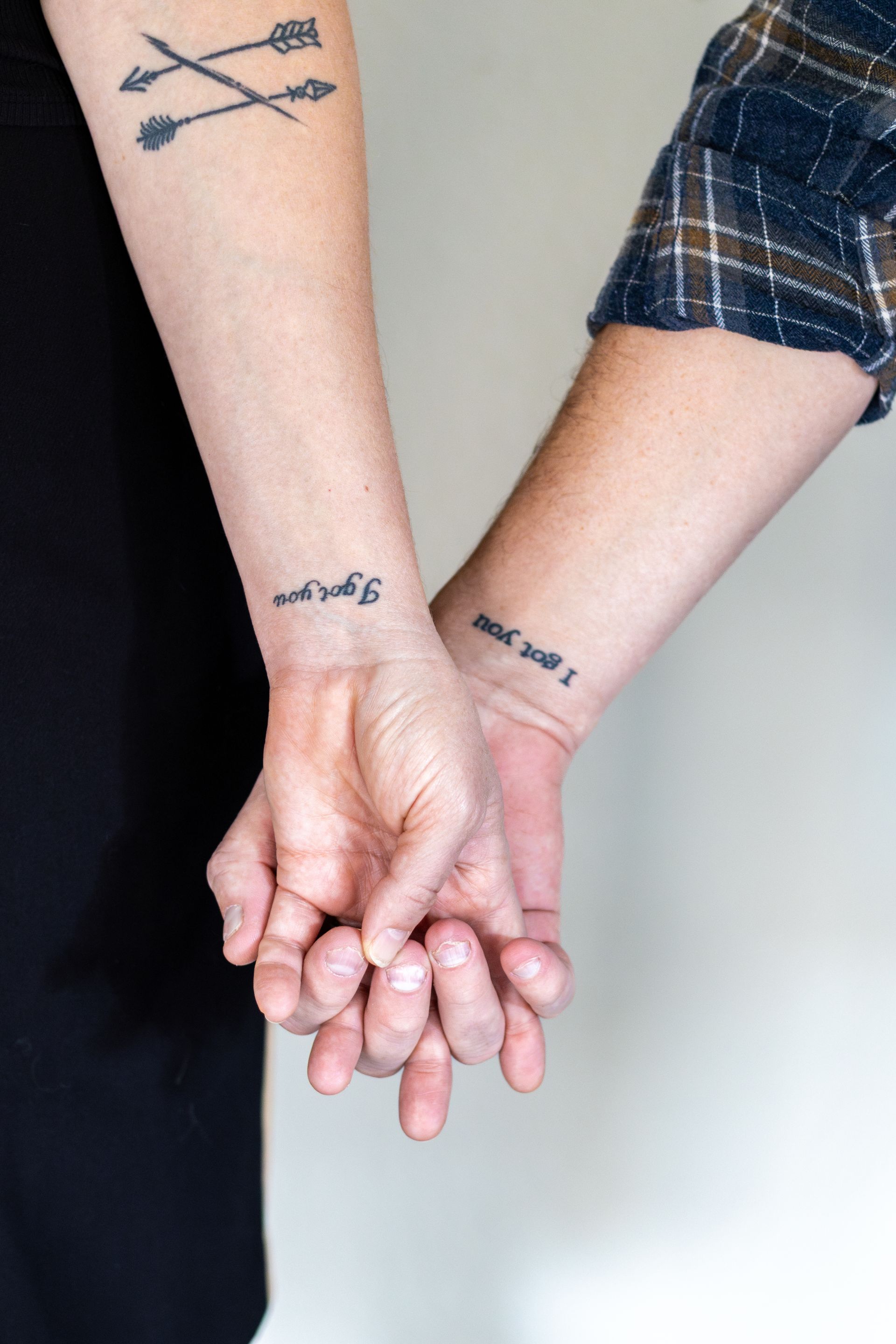 A couple with tattoos on their wrists holding hands