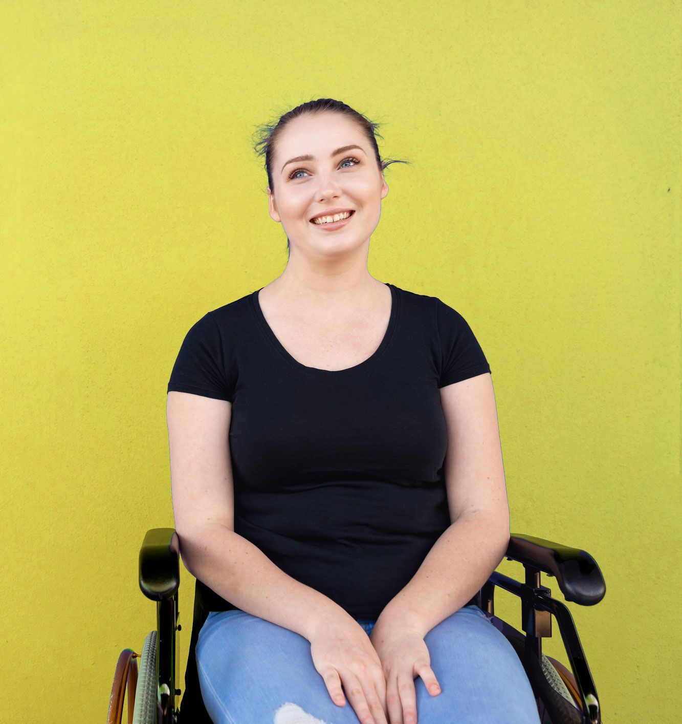 Woman in a wheelchair smiling against a yellow background, wearing a black shirt and jeans. Woman in a wheelchair smiling against a yellow background, wearing a black shirt and jeans.