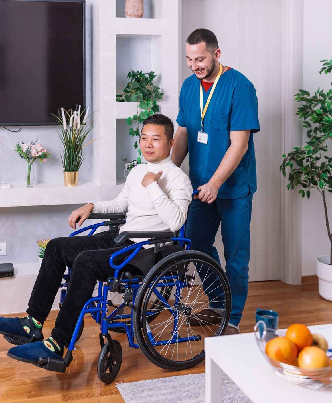 Man in wheelchair, with caregiver pushing him indoors. The man smiles, and they are near a table with fruit. Man in wheelchair, with caregiver pushing him indoors. The man smiles, and they are near a table with fruit.