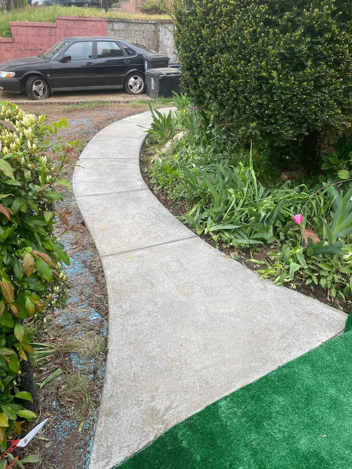 A concrete walkway with a car parked on the side of it.