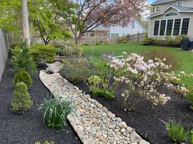 A rocky path leading to a house in a backyard.