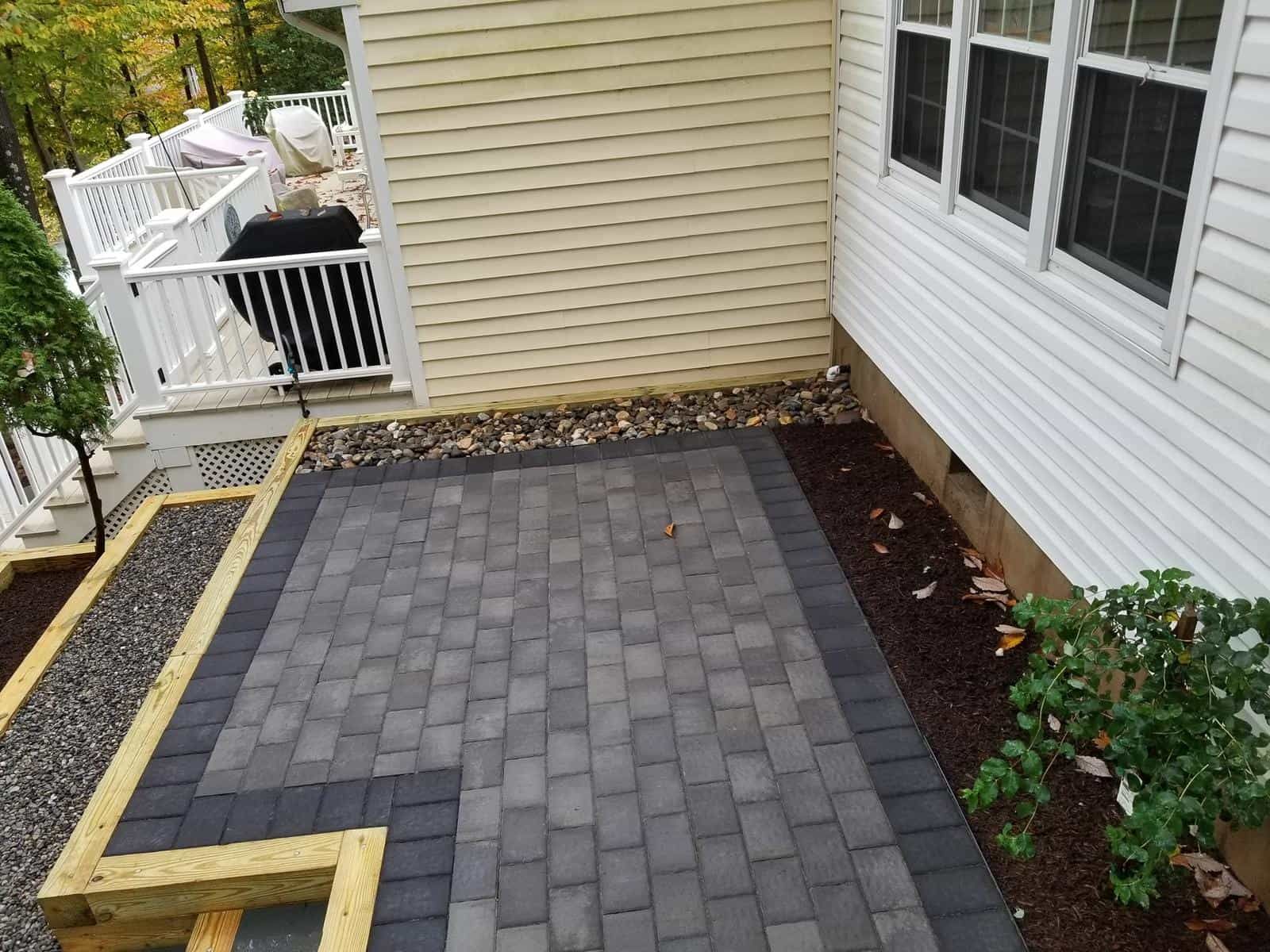A patio with bricks and a white house in the background.