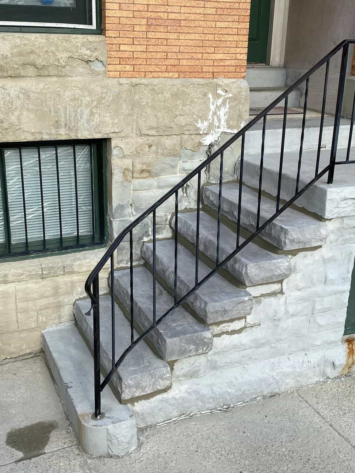 A set of stairs with a metal railing leading up to a brick building.