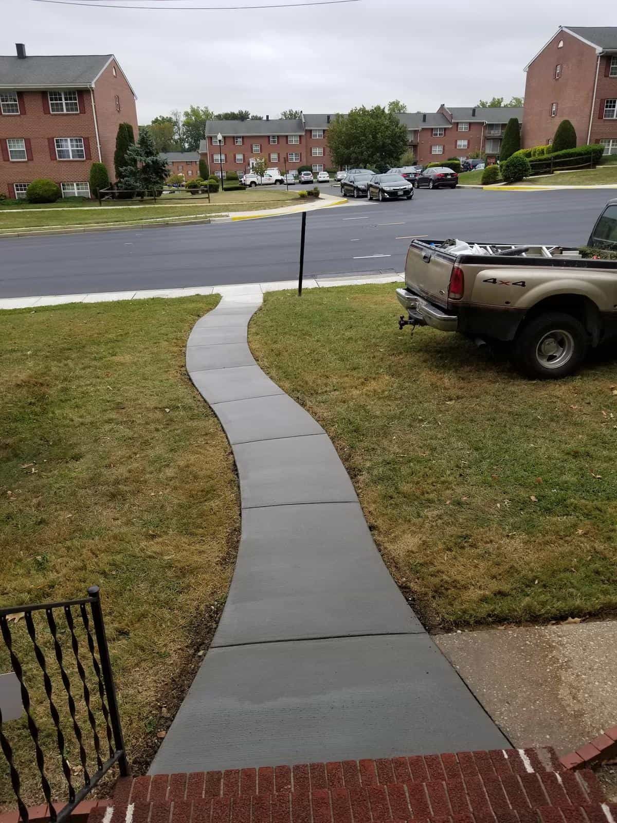 A truck is parked on the side of the road next to a sidewalk